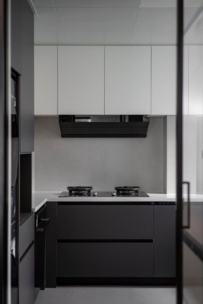 Sleek modern kitchen with black and white cabinetry, minimalistic design, and gas stove.